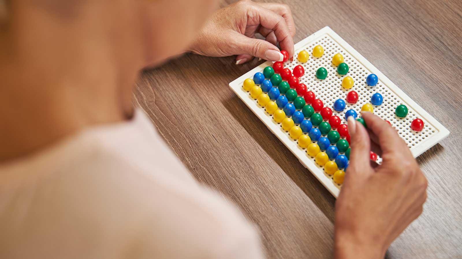 woman arranging colored pegs on a board representing occupational therapy program at Clarkson university 